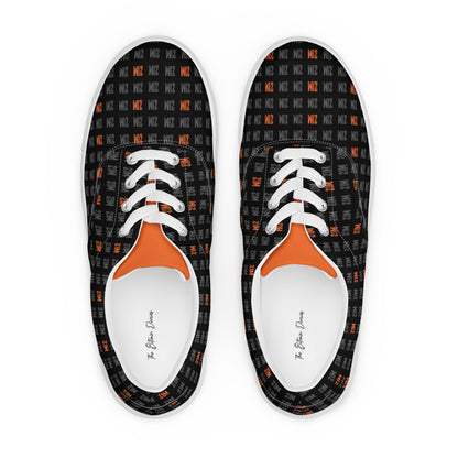Pair of black sneakers with orange 21 million accents and white laces on a white background