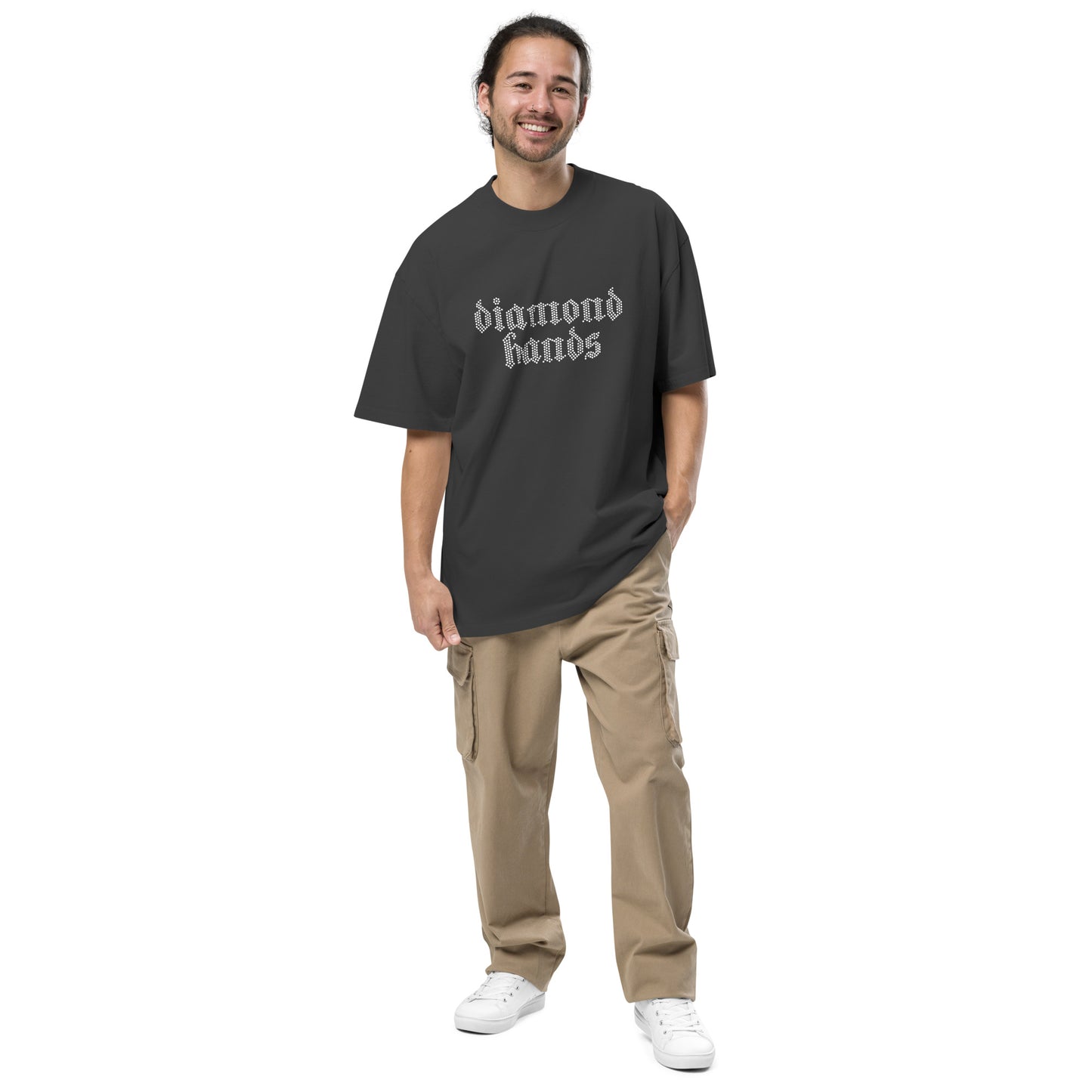 Man wearing a black t-shirt with 'diamond hands' text and beige pants on a white background