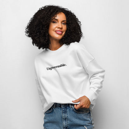 Woman wearing a white sweatshirt with 'Ungovernable.' text on a plain background