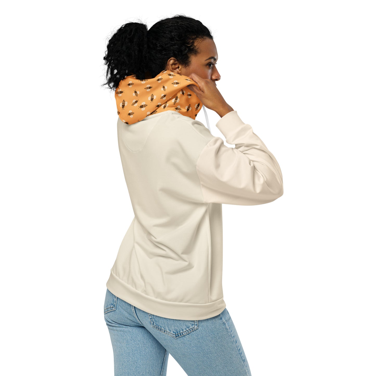 Woman wearing a beige hoodie and light blue jeans with a patterned orange hoood with bitcoin bees on a white background