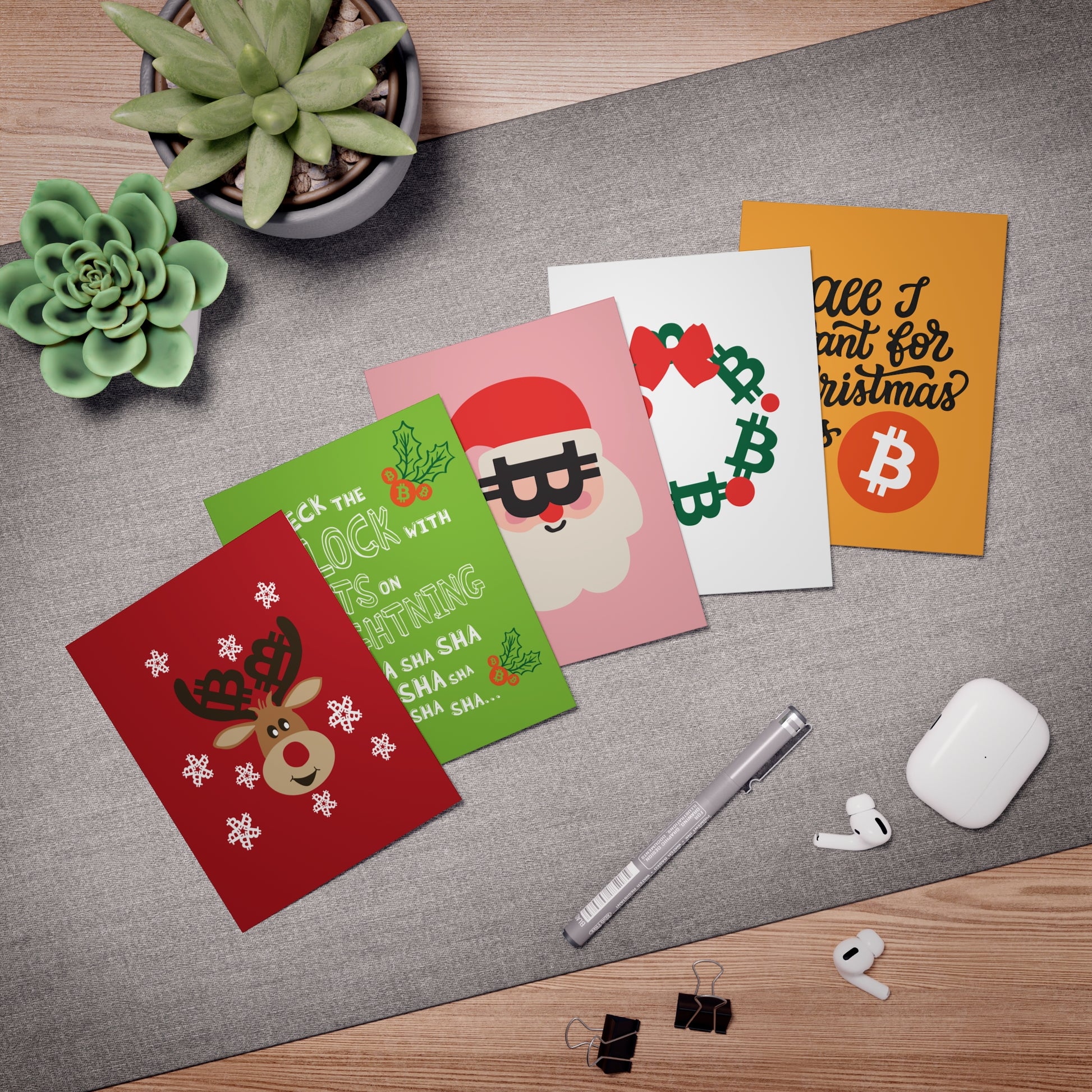 Set of Bitcoin Christmas-themed greeting cards on a desk with office supplies.