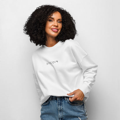 Woman wearing a white sweatshirt with 'BITCOIN' text on a plain background