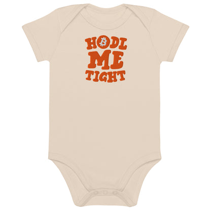 Beige baby onesie with 'HODL ME TIGHT' text in orange on a white background