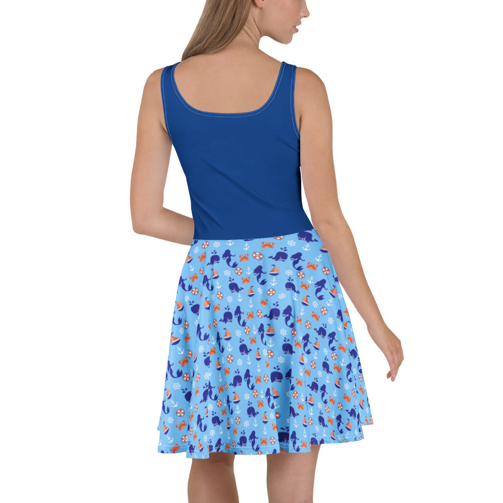 Woman wearing a blue dress with a nautical patterned skirt on a white background